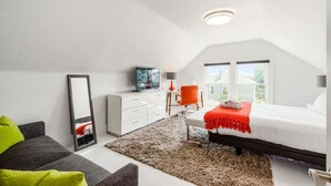 A modern bedroom with a bed, a desk, a chair, a dresser, and a large window.