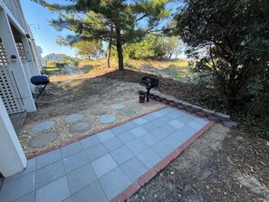 A patio with stone stepping stones, a barbecue grill, and a grill basket.