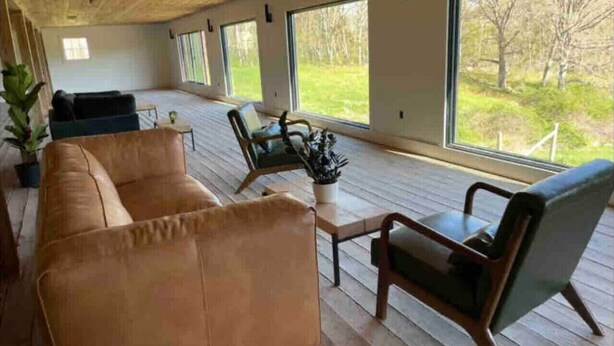 A spacious room with a wooden floor, large windows, a sofa, and two chairs. - Dome 3 at Come Spring Farm Glamping - Alpaca Farm (Union)