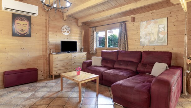 Un intérieur en bois comprenant un canapé, un téléviseur, une table et des œuvres d’art accrochées aux murs.