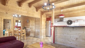 Un intérieur en bois comprenant un coin repas, une cuisine et un canapé rouge.