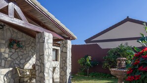 Un bâtiment en pierre doté d’un patio couvert, d’un espace extérieur aménagé pour s’asseoir et d’un jardin avec une fontaine.