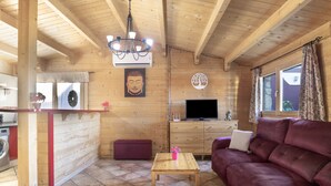 Un intérieur en bois comprenant un canapé, une table, un téléviseur et une statue de Bouddha.