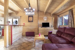 Un interior de madera con un sofá, una mesa, un televisor y una estatua de Buda.