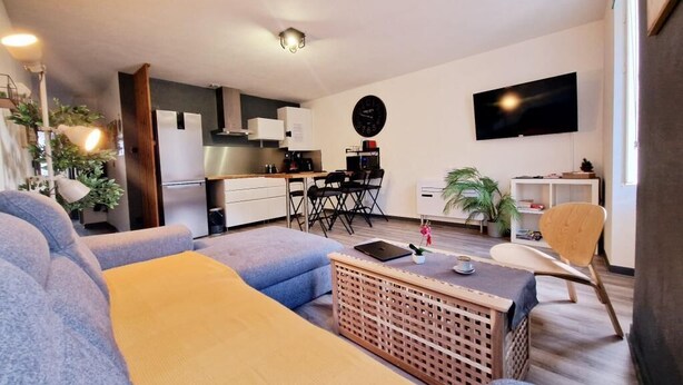 A modern living room with a sofa, coffee table, and a TV mounted on the wall. - LE DRÔMARDÈCHOIS *** Gîte meublé Ardèche / ECOLODGITE (TOURNON)