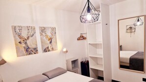 A bedroom with a bed, a wardrobe, a mirror, and two wall-mounted paintings of deer. - LE DRÔMARDÈCHOIS *** Gîte meublé Ardèche / ECOLODGITE (TOURNON)
