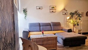 A modern living room with a grey sofa, a wooden coffee table, and a plant. - LE DRÔMARDÈCHOIS *** Gîte meublé Ardèche / ECOLODGITE (TOURNON)