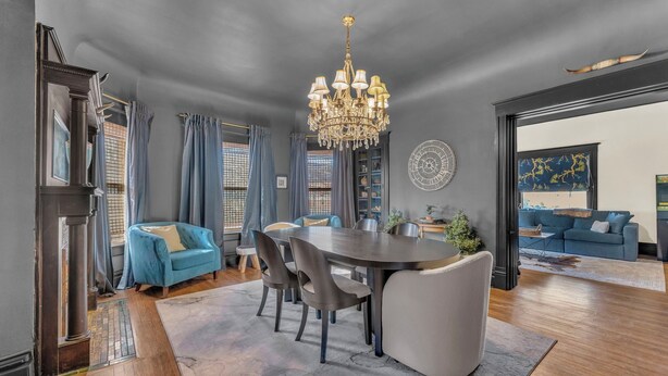 A spacious dining area with a large round table, modern chairs, and a chandelier.