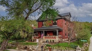 A two-story brick house with a stone foundation, a front porch, and a flag.