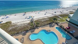 A beach view with a swimming pool and lounge chairs. - Palacio 703 | Oceanfront Resort Amenities | My Beach Getaways (Pensacola)