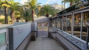 A gated entrance to a hotel with a view of palm trees and buildings in the background.