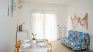 Un coin repas avec une table dressée pour quatre personnes, un canapé et un téléviseur posé sur un meuble.