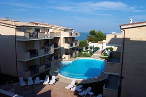 Un edificio a più piani con piscina circondata da sedie a sdraio.