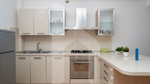 Une cuisine moderne avec des armoires blanches, une cuisinière à gaz, un four encastré et un évier.
