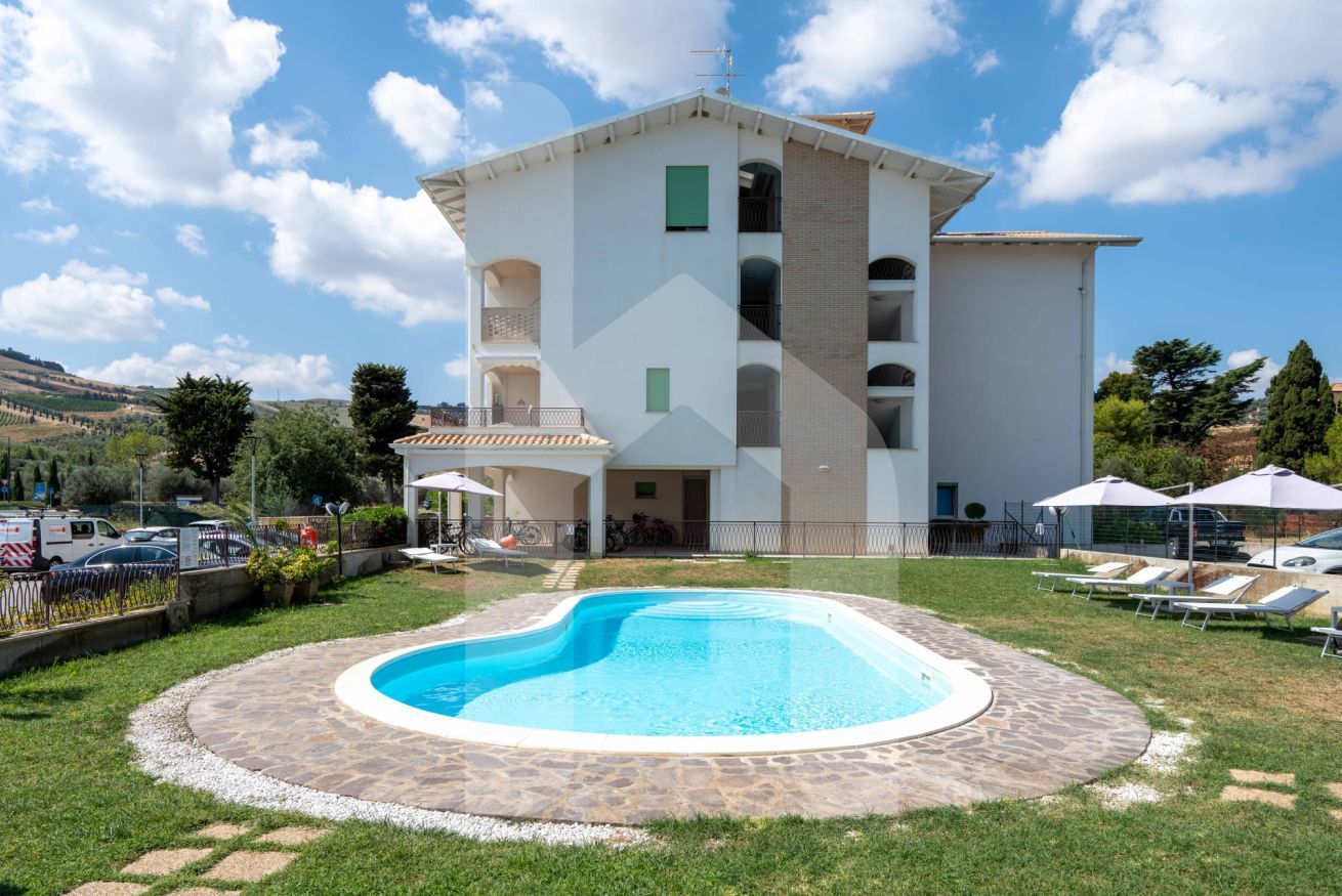 Un edificio a due piani con una piscina in primo piano.