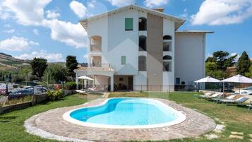 Un edificio a due piani con una piscina in primo piano.
