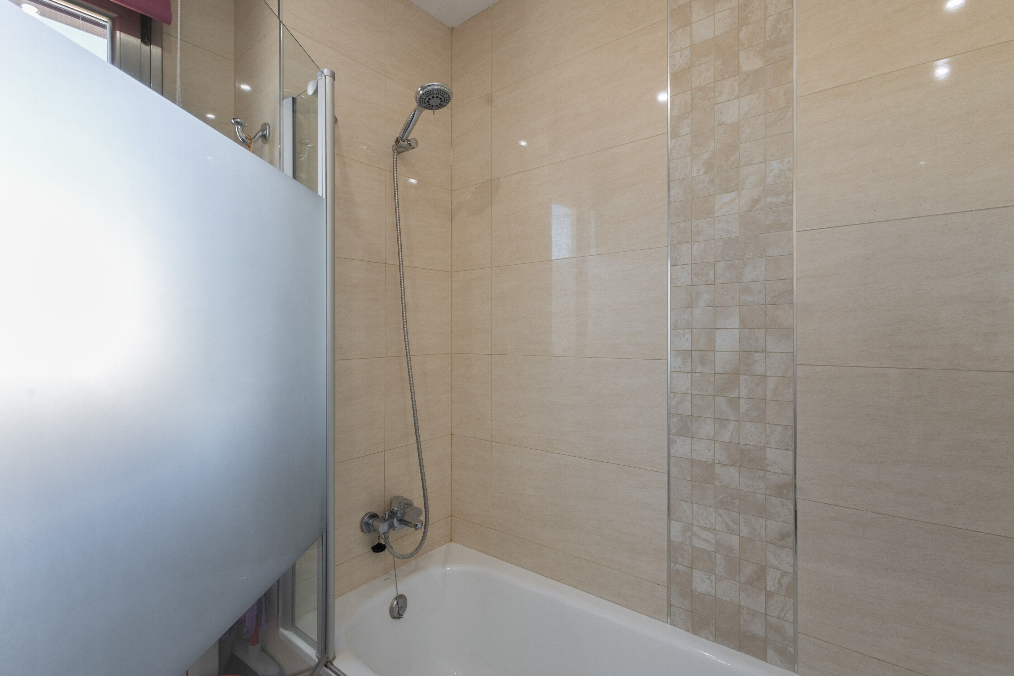 Un bagno con una vasca, una doccia e pareti piastrellate.