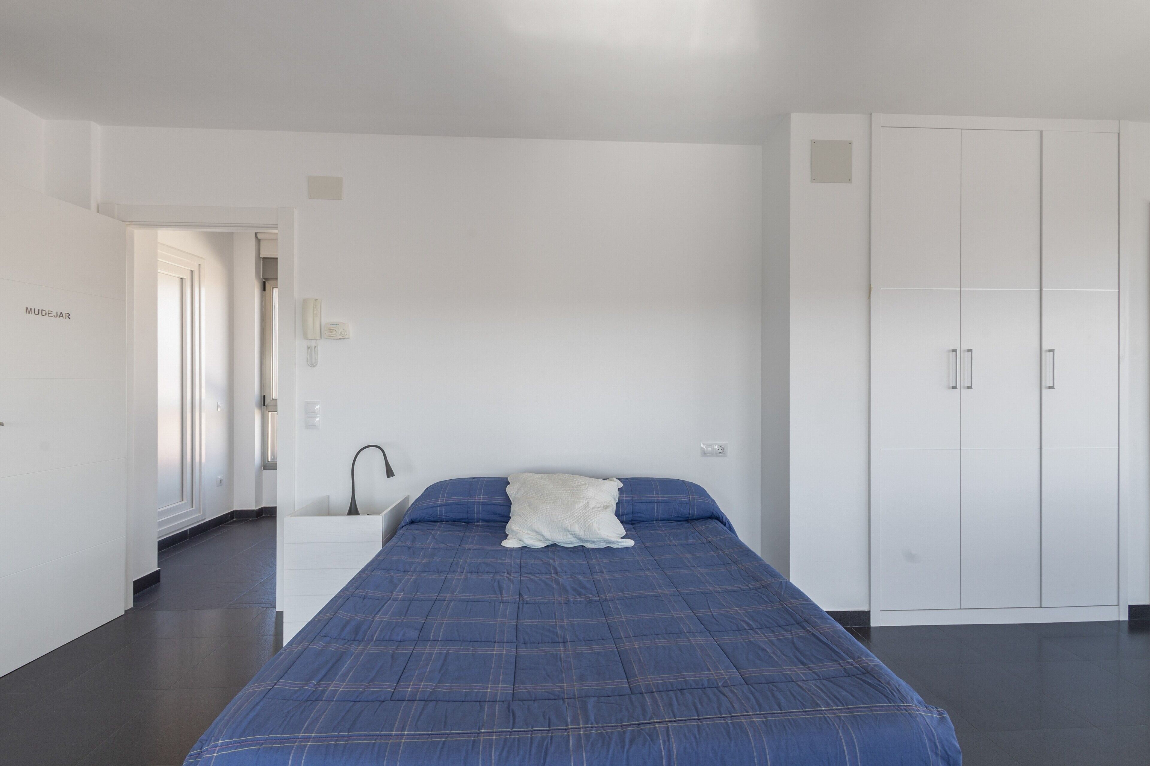 A bedroom with a bed, white wardrobe, and a nightstand.