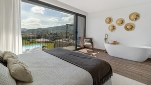 Un dormitorio con una cama grande, una bañera y un balcón con vistas a la piscina.