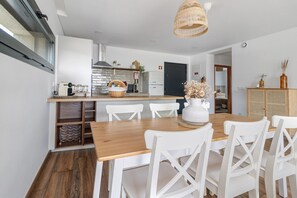 Una cocina moderna con armarios blancos, una mesa de comedor de madera y sillas blancas.