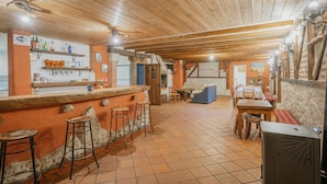 A rustic interior with a bar area, stools, a wooden ceiling, and a tiled floor. - Rural House 'El Pico Llanillo' in Ribera del Duero with Private Pool (SAN MIGUEL DEL ARROYO)