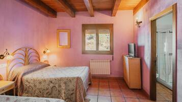 Een slaapkamer met twee bedden, een houten plafond, een raam, een radiator en een televisie.