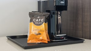 Una cafetera y un paquete de café tostado oscuro Cafe Valet sobre una encimera.