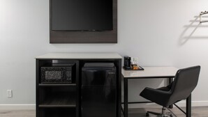 Espacio de oficina compacto con escritorio, silla y un refrigerador negro.