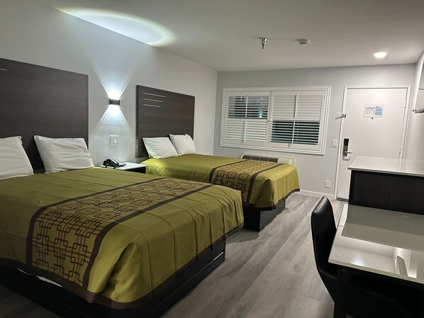 Quarto de hotel com duas camas, uma escrivaninha e uma cadeira.