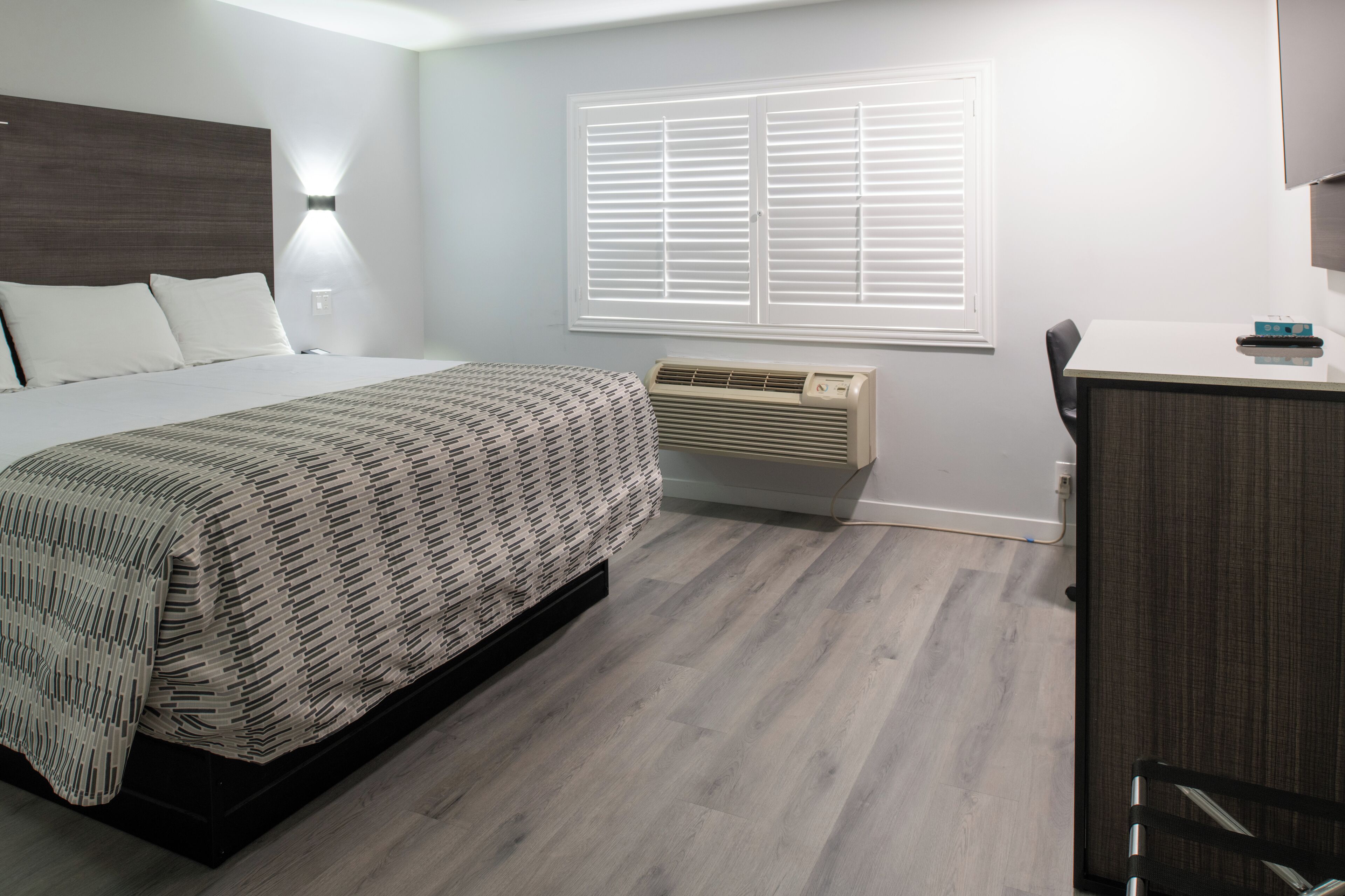 Un dormitorio con cama, escritorio y ventana con persianas.