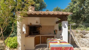 A small outdoor kitchen with a tiled roof, a built-in oven, and a table with a colorful tablecloth. - Holiday Home 'Calme Et Sans Vis À Vis' with Private Pool, Private Terrace and Wi-Fi (Salon-de-Provence)
