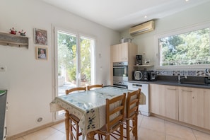 Una cocina con una mesa de comedor, sillas, armarios, estufa y una ventana.