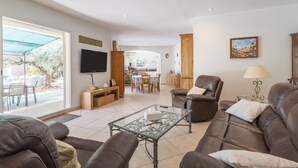 A living room with a sofa, a glass coffee table, a TV, and a dining area in the background. - Holiday Home 'Calme Et Sans Vis À Vis' with Private Pool, Private Terrace and Wi-Fi (Salon-de-Provence)