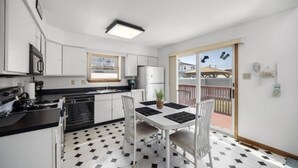 Cocina compacta con armarios blancos, encimera negra y comedor con mesa y sillas.