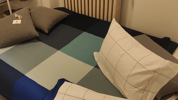 A bed with a geometric-patterned bedspread and several pillows. - Bèz Apartment in Milan Tortona street Fashion design district  (Milano)