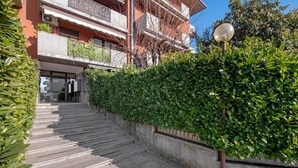 Eine Treppe führt zu einem Gebäude mit Balkonen, umgeben von viel Grün.