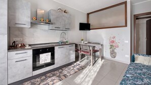 Eine moderne Küche mit Backofen, ein Essbereich mit Tisch und Stühlen sowie ein an der Wand montierter Fernseher.