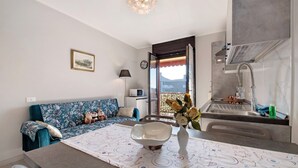 Eine moderne Küche mit Spüle, ein Essbereich mit Tisch und Stühlen, ein Sofa mit Blumenmuster und eine dekorative Vase mit Blumen.