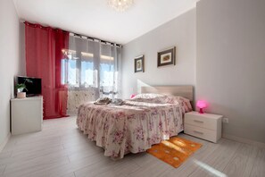 A bedroom with a bed, bedside table, TV, and curtains. - Apartment 'Alle Porte Di Bergamo' with Balcony and Wi-Fi (Seriate)