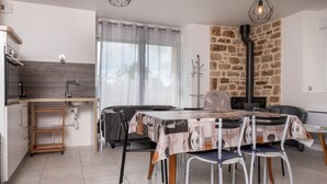 A modern kitchen with a built-in oven, a dining area with a table and chairs, and a stone wall. - Holiday Home 'La Longère Du Cosquer' with Private Terrace, Garden & Wi-Fi (Baden)