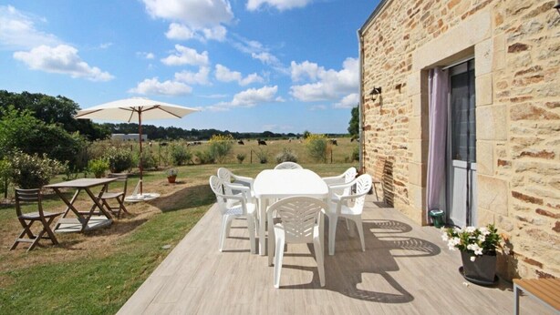 A patio with a stone building, outdoor furniture, and a view of a field. - Holiday Home 'La Longère Du Cosquer' with Private Terrace, Garden & Wi-Fi (Baden)