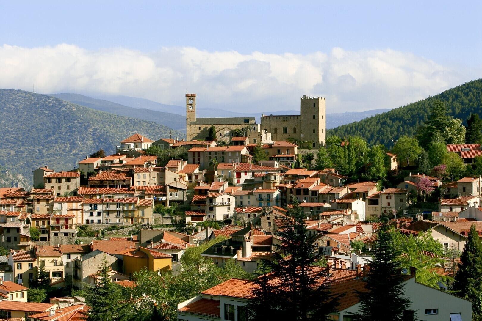 Un pueblo en una ladera con edificios tradicionales, una torre destacada y una estructura que parece un castillo.