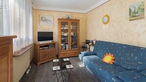 Una sala de estar con televisor, aparador de madera, sofá y una pequeña mesa.