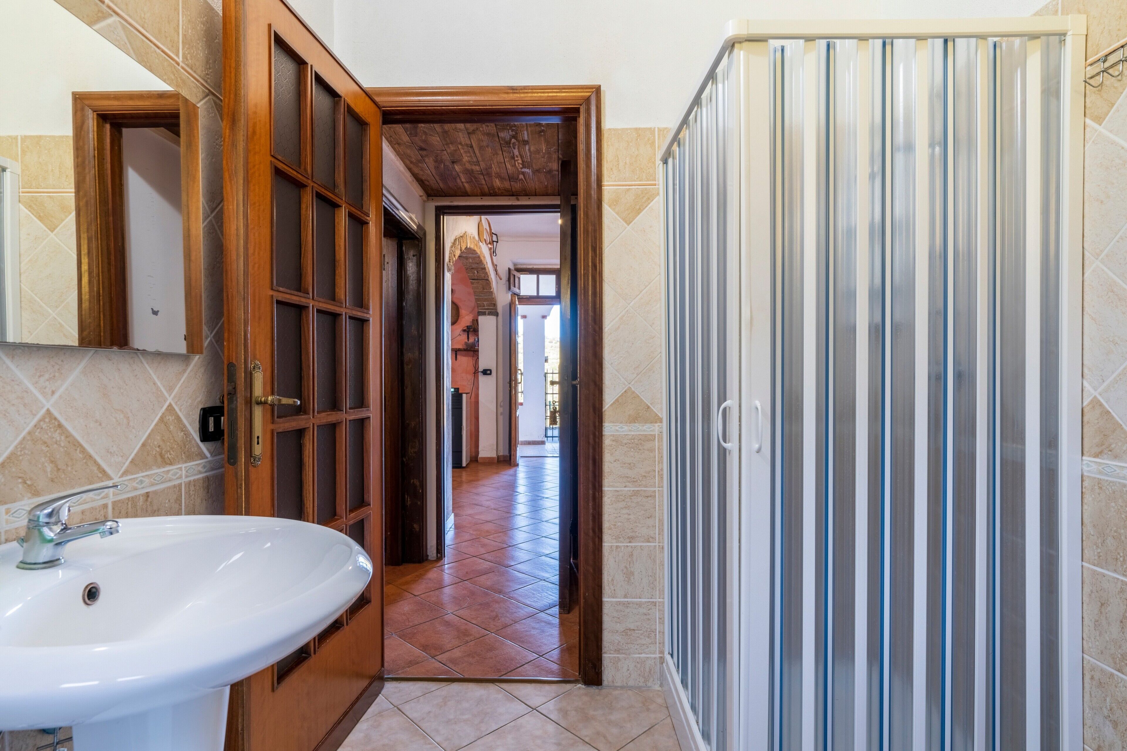 Une salle de bain avec un lavabo, une douche dotée d’un rideau à rayures et un sol carrelé.