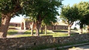 Un muro de piedra, un sendero y un edificio con arcos.