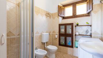 Un bagno con doccia, WC, bidet e lavandino.