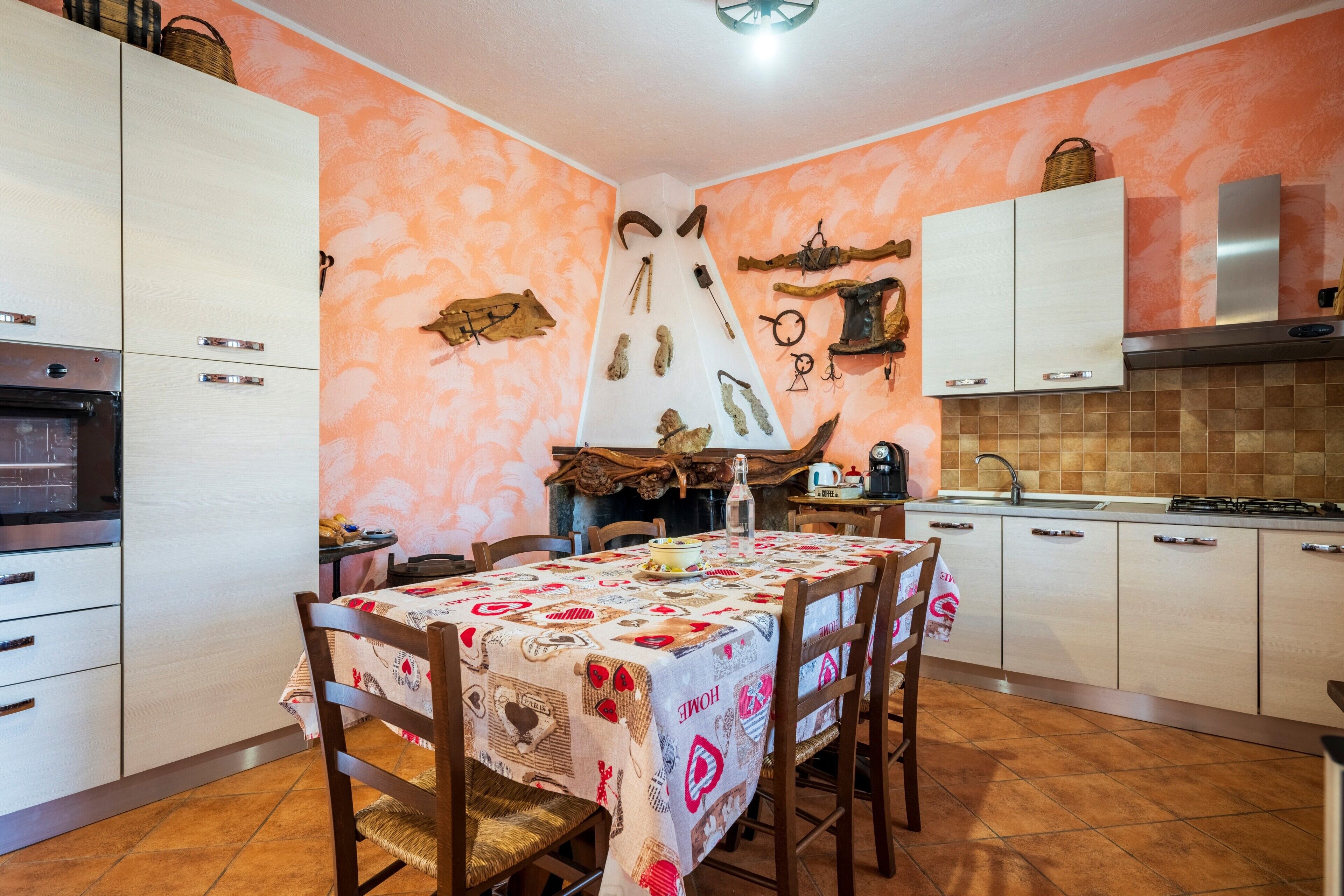 A kitchen with a dining table, chairs, cabinets, and a tiled backsplash.