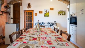 Comedor con una larga mesa, sillas, un candelabro y un arco de ladrillo.