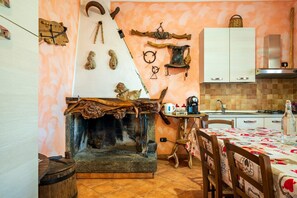 Una cocina rústica con chimenea de piedra, utensilios de madera y una estación para café.