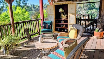 A wooden deck with wicker furniture, a stone table, and potted plants.